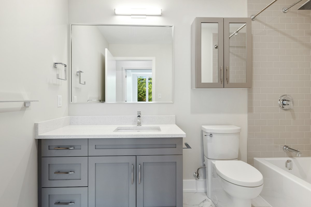 Clean bathroom with gray vanity and white tub