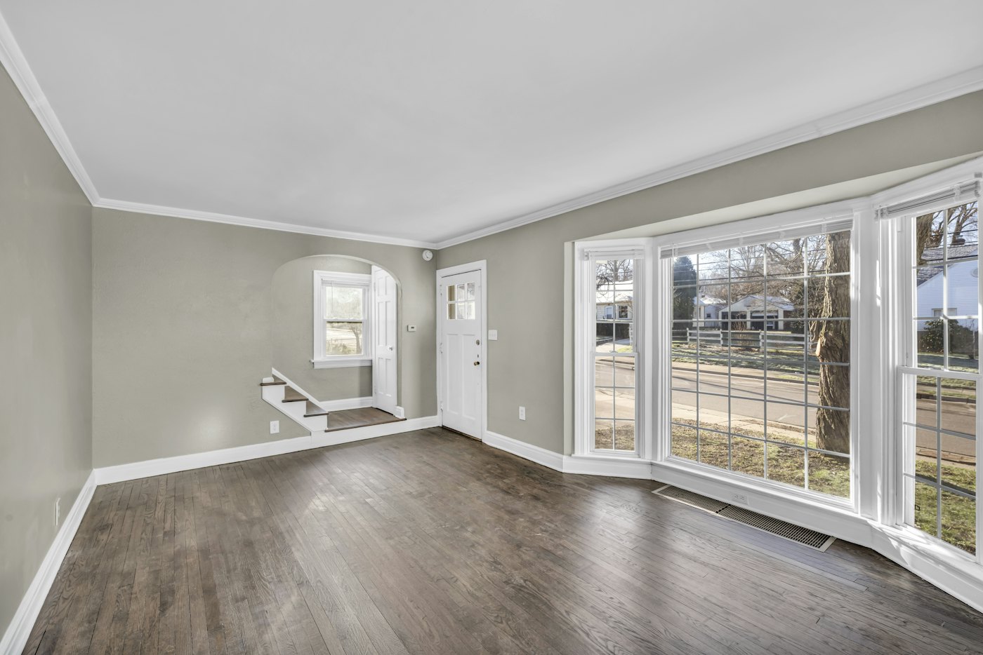 Empty living room with a bay window and hardwood floors, ready for move-in
