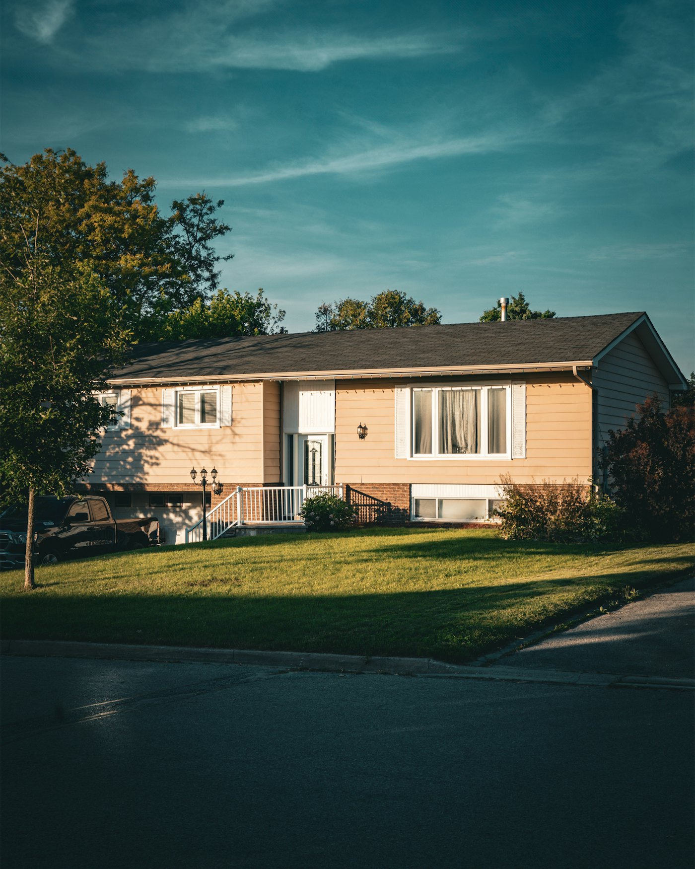 Bi-level home with front lawn in evening light