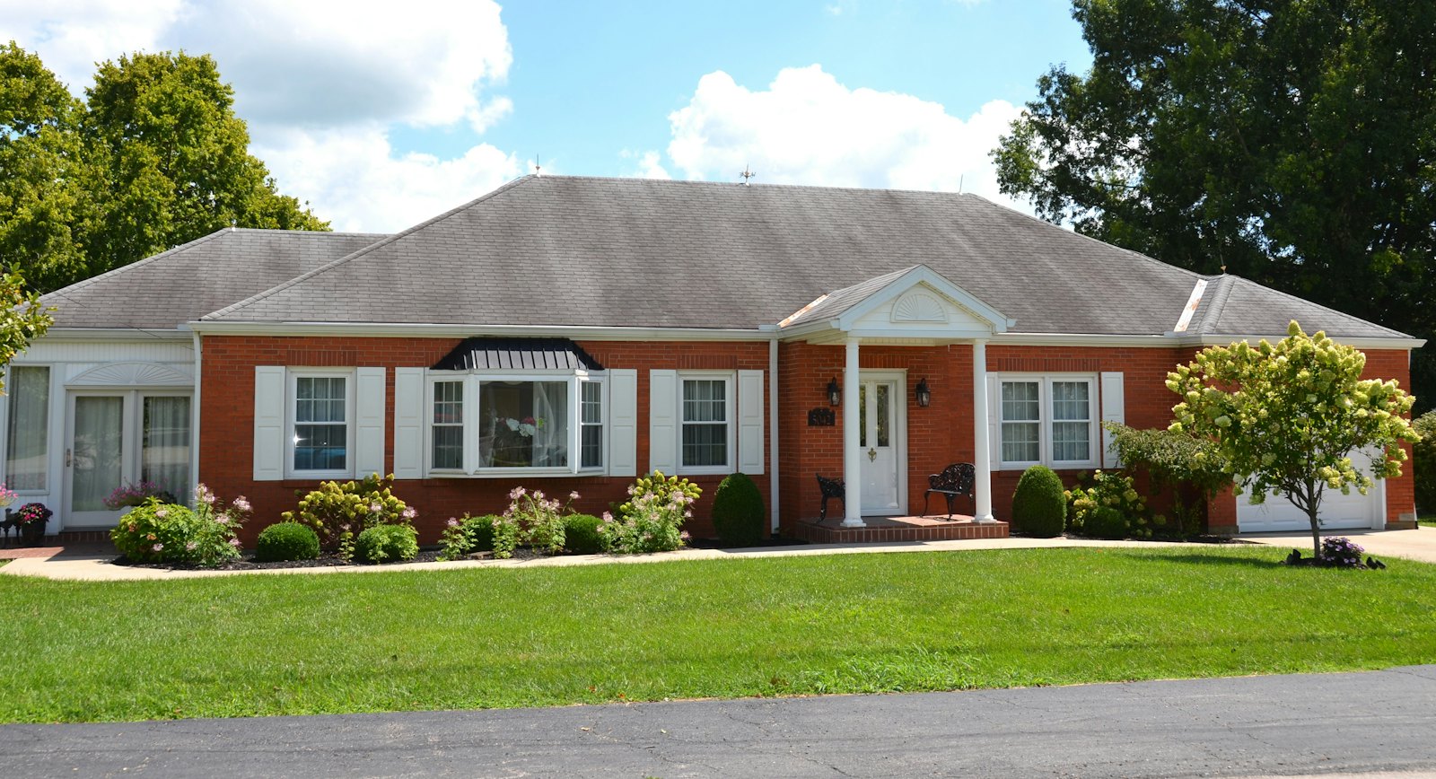 Single-story red brick ranch home with white shutters