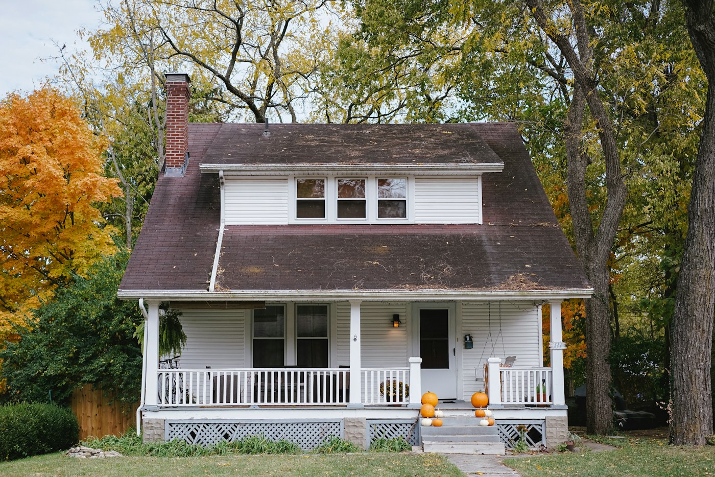 Bungalow with a covered front porch and autumn trees